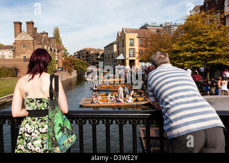A girl in a panda print dress and a man watch punting on the River Granta from Magdalene Street bridge, Cambridge, Cambridgeshire, UK Stock Photo