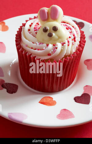 Easter cupcake with white chocolate bunny rabbit on set on plate with hearts on Stock Photo