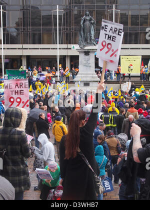 A woman holds a placard in the air proclaiming 'We are the 99%' during a protest in guildhall square, Portsmouth, England.
