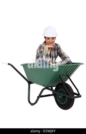 Tradeswoman sitting in a wheelbarrow Stock Photo