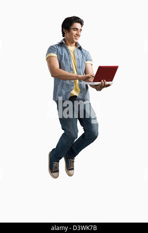 College student using a laptop and jumping Stock Photo