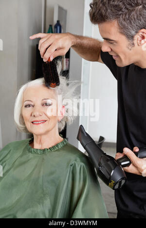 Hairdresser Blow Drying Woman's Hair Stock Photo