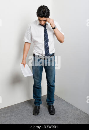College student standing in the corner looking worried Stock Photo