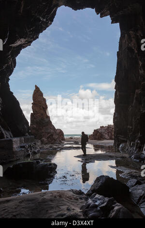 Needle Rock with person standing in Plemont Cave, Jersey, Channel Islands, UK Stock Photo
