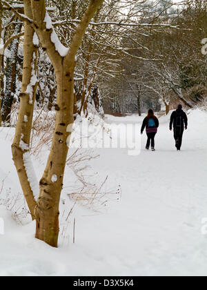 Couple enjoying winter walking in deep snow on the High Peak Trail near Wirksworth Derbyshire Dales Peak District England UK