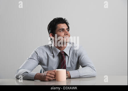 Businessman lost in thoughts while drinking coffee Stock Photo