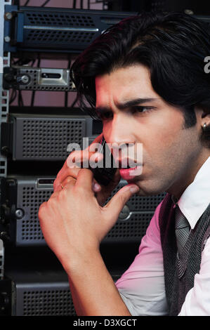 Networking engineer talking on a mobile phone in a server room Stock Photo