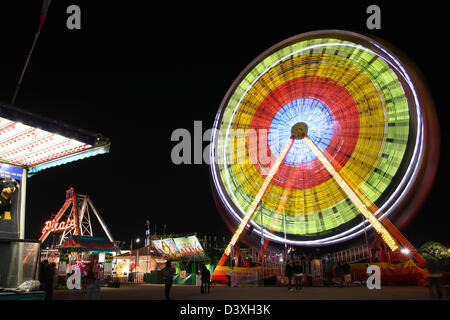 Ferris Wheel at night Fair Carnival with Rides Stock Photo