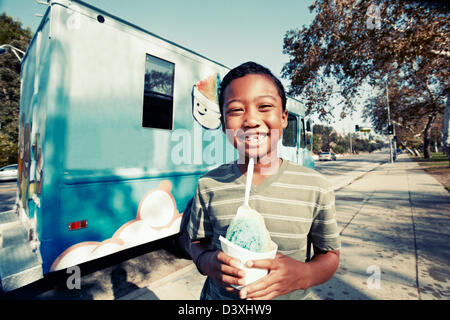 Mixed race boy eating ice cream from truck Stock Photo