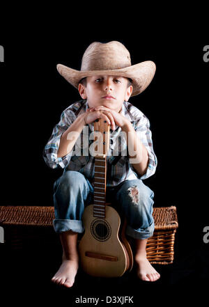 A boy wearing a hat with a guitar on a black background Stock Photo