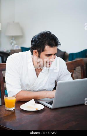 Businessman working on laptop at breakfast table Stock Photo