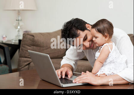 Man using a laptop with his daughter sitting with him Stock Photo