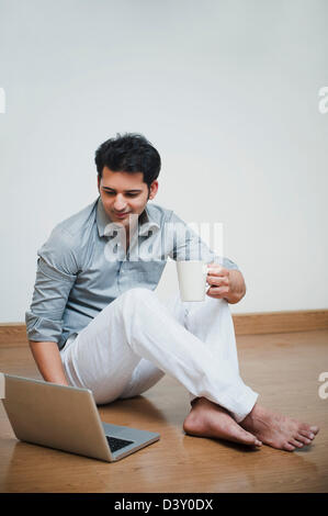 Man drinking coffee and using laptop Stock Photo