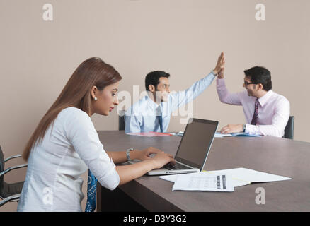Businesswoman using a laptop with her colleagues in the background Stock Photo