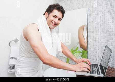 Man using a laptop in the bathroom Stock Photo