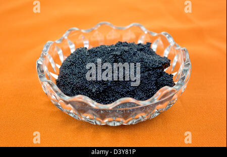 A small glass bowl filled with black caviar on a cloth background. Stock Photo