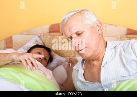 Unhappy tired senior couple in bed waking up. Stock Photo