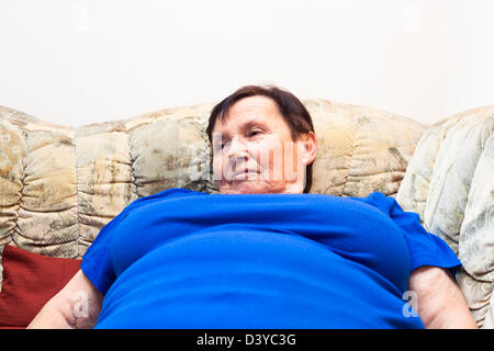 Close up of obese elderly woman lying on sofa. Stock Photo