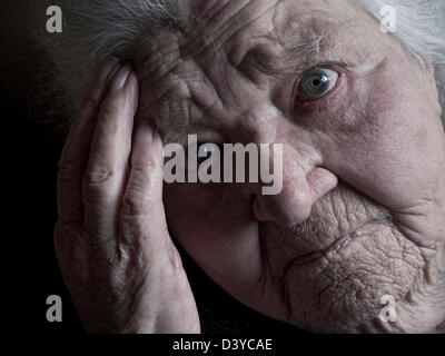 Elderly old age 100 years pensive lady close view face hand portrait looking directly at camera. Stock Photo