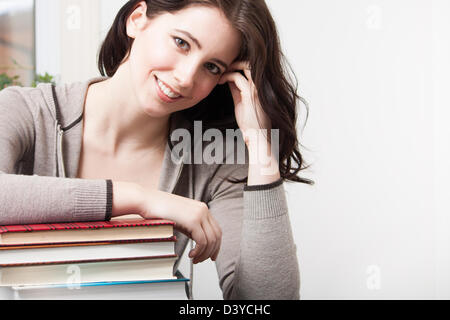 A beautiful college girl leans on a stack of books Stock Photo