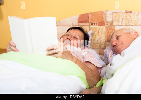 Close up of happy senior couple reading book in bed. Stock Photo
