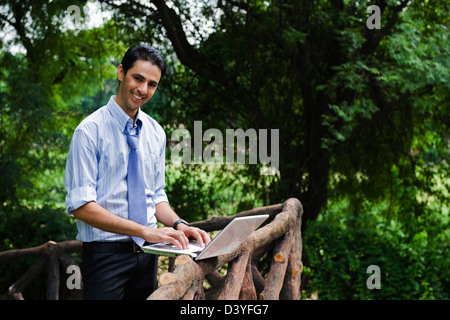 Businessman using a laptop in a park Stock Photo