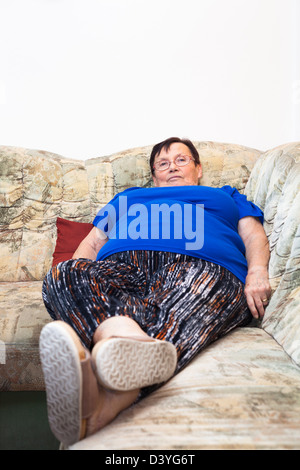 Portrait of obese elderly woman lying on sofa. Stock Photo