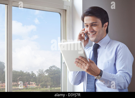 Businessman using digital tablet and talking on a cell phone Stock Photo