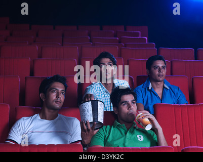 Youngsters enjoying movie with popcorns in a cinema hall