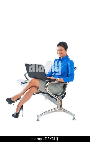 Businesswoman sitting on a bench and using a laptop Stock Photo