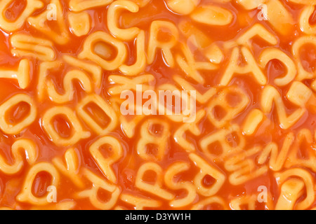 Background of pasta shaped alphabet letters in a tomato sauce Stock Photo