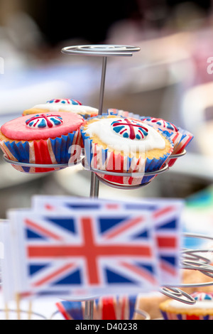 Close-up of cupcakes with union flag icing and cases. Selective focus with mini Union flags out-of-focus in the foreground. Stock Photo