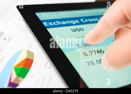 Hand on screen tablet pc with currency exchange information Stock Photo