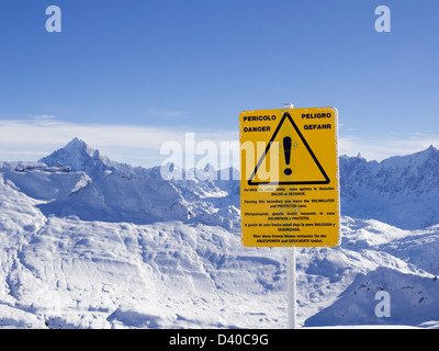 Off piste warning sign and view from Les Grandes Platieres in Le Grand Massif ski area to snowcapped mountains in French Alps Stock Photo