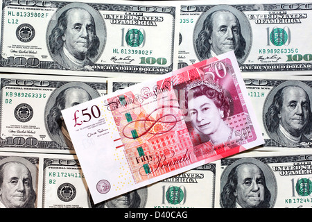 20 and 50 Pounds banknotes with portrait of Queen Elizabeth II and 100 Dollars banknotes in background Stock Photo