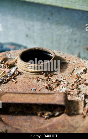 Close up of rusty oil can showing texture against blue/grey background Stock Photo