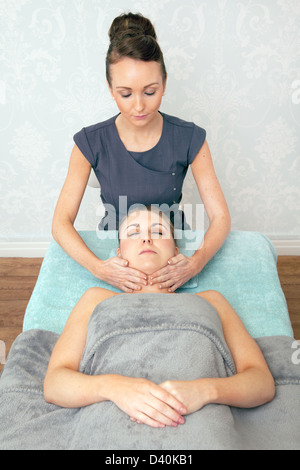 Young woman having a relaxing face massage by a female beautician. Stock Photo