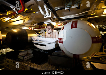 Man in bunk with torpedoes in Nuclear Submarine HMS Talent Stock Photo