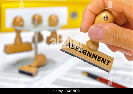 rubber stamp in hand marked with assignment Stock Photo