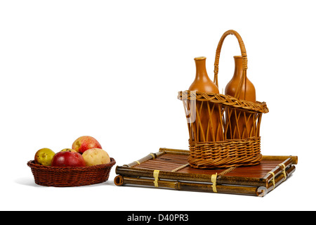 Wattled baskets with apples and ceramic wine bottles on a bamboo support Stock Photo