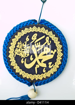 Closeup of blue velvet Muhammad pendent isolated on white background Islamic calligraphy transliterated as 'Muhammad Rasulullah' Stock Photo