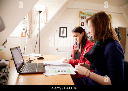 Two women students studying together at their desk with laptop computer in university room, England UK Stock Photo