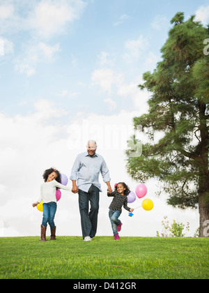 Man walking with granddaughters in park Stock Photo