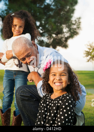 Man playing with granddaughters outdoors Stock Photo