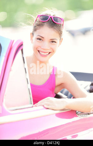 Portrait of beautiful young mixed race woman in pink old retro car smiling in summer Havana, Cuba Stock Photo