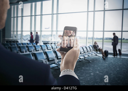Businessman holding cell phone in airport Stock Photo