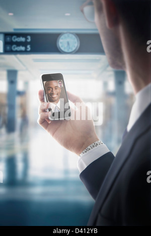 Caucasian businessman text messaging on cell phone in airport Stock Photo