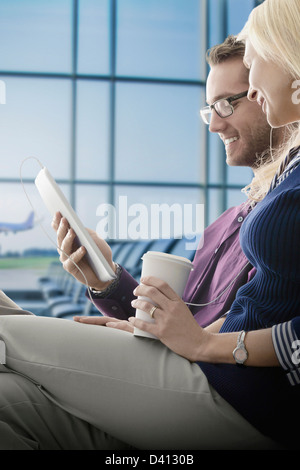 Caucasian couple using digital tablet in airport Stock Photo