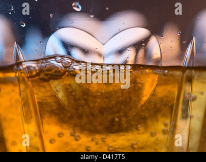 Detail of a cut glass champagne goblet with a heart on the side and drink being poured Stock Photo
