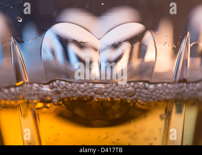 Detail of a cut glass champagne goblet with a heart on the side and drink being poured Stock Photo
